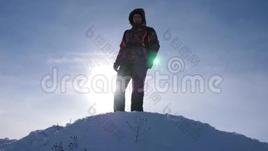 带背包的旅行者在日落的背景下从山上下来。 游客<strong>站在</strong>白雪皑皑的<strong>山顶</strong>上